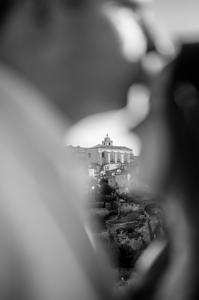 Black and white photo of a Couple embracing at sunrise on the hillside overlooking Gordes, Provence